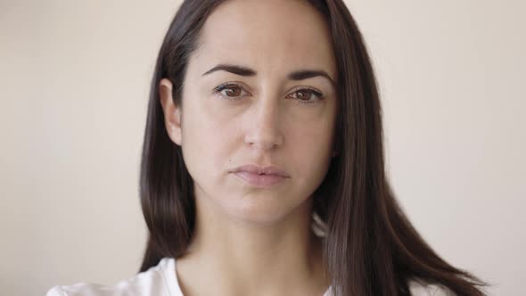 Portrait of Serious Young Adult Woman Looking at Camera Against White Background