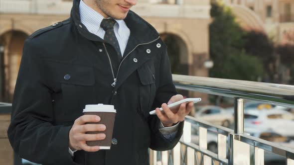 A Well-groomed Man Is Typing Something in His Mobile Phone