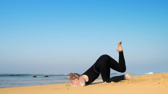 Young Woman Raises Leg in Yoga Pose at Endless Blue Ocean