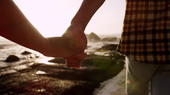 Couple holding hands at beach during sunset 4k
