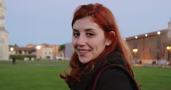 Young University Girl with Backpack in an Italian Square Smiles at the Camera