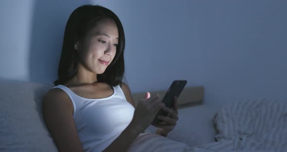 Young Woman using cellphone on bed