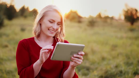 Smiling Woman Using Digital Tablet Outdoors in Summer