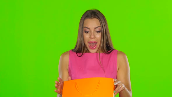 Woman Looks at the Package and Consider Buying. Green Screen. Close Up