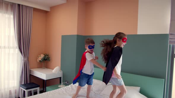 Girl and Boy Superheroes are Jumping in Room on Bedin Children's Room Two Children in Red and Blue