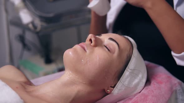 Female Cosmetologist is Removing a Special Mask From Woman's Face and Cleaning Her Face with Cotton