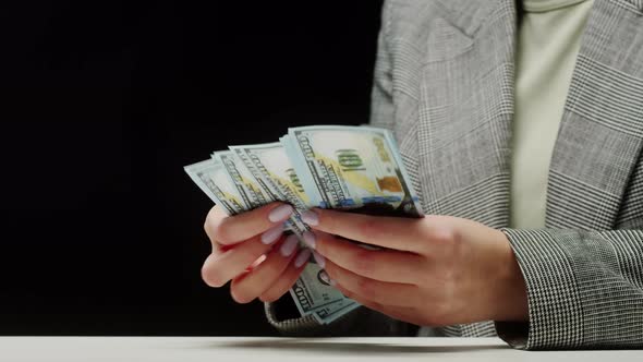 Counting American Hundred Dollar Banknotes on Black Background