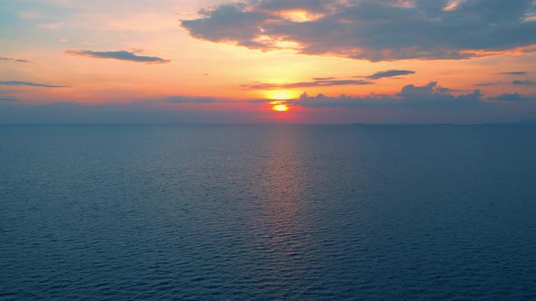 4K drone flying over the sea, sunset on the horizon.