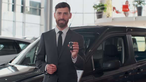 Professional Car Salesman Smiling Happily Holding Car Keys Standing in Front of New Cars at the