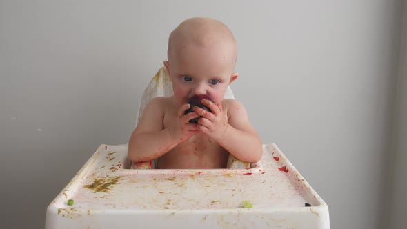 Cute Baby Girl Soiled in Food While Eating Plum.