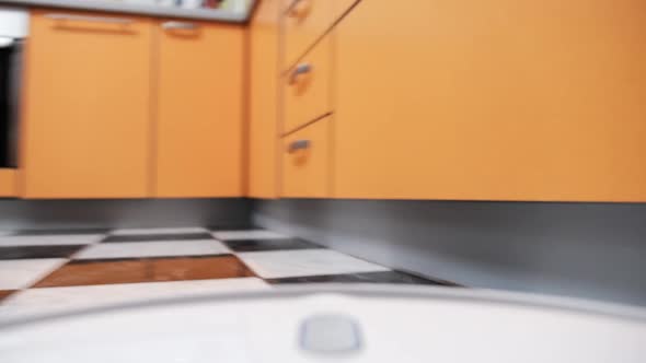 POV View of Robot Vacuum Cleaner Cleans Tiles Floor in House at Kitchen