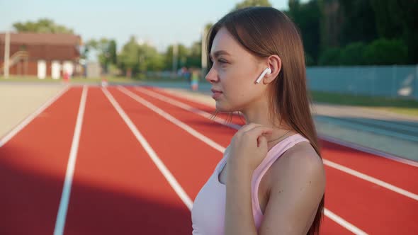 Closeup Runner Woman Standing with Phone in Earphones at Stadium