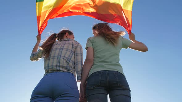 Couple with Lgbt Flag Standing Under Bright Sky
