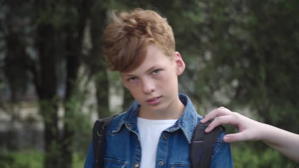 Nerd Redhead Schoolboy Looking at Camera As Unrecognizable Classmates Pushing Him. Portrait of