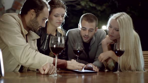Group of Friends Uses Tablet While Drinks Wine in Rural Farm House Tuscany Italy at Night Slow