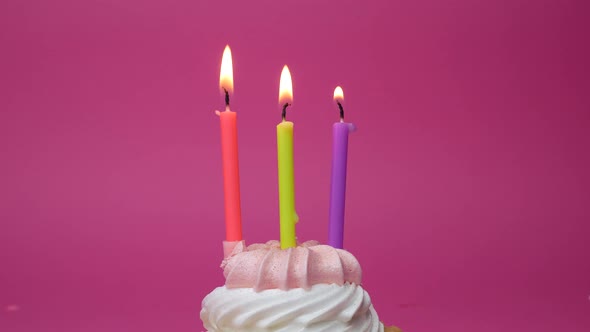 Birthday Cupcake with Candles and Birthday Decorations on Pink Background