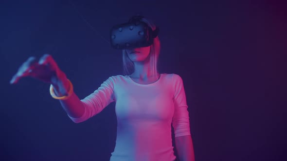 Young Attractive Girl in Virtual Reality Headset, Takes Object, Holds and Look on It, Standing in