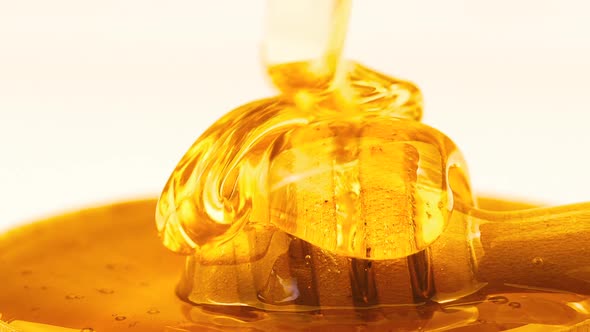 Liquid Organic Honey Dripping from Above to a Honey Dipper in Wooden Bowl