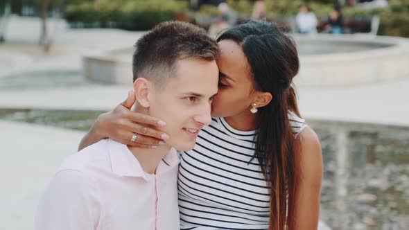 Pretty Black Lady Whispering Something in Boyfriend's Ear and Then Showing Keep Silence Gesture to
