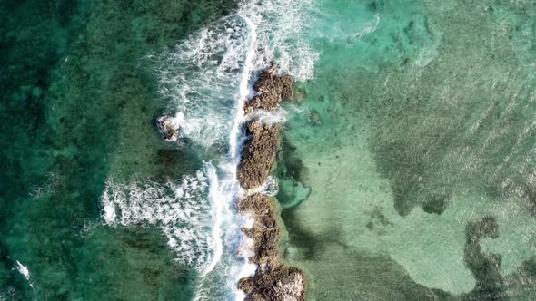 Birdseye Aerial View of Tropical Sea Waves Breaking on Small Rocky Islet, Top Down Drone Shot