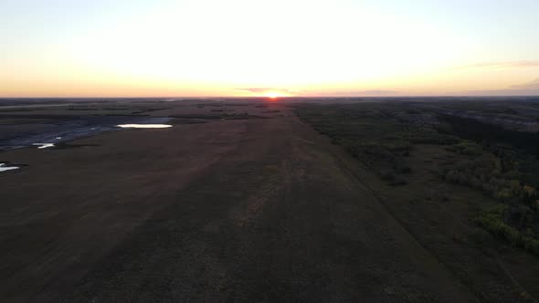 Drone ascending revealing the sun setting over the horizon of the Alberta countryside, Canada.