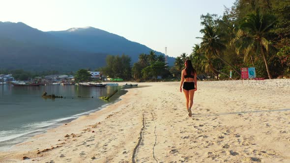 Ladies posing on idyllic coast beach voyage by aqua blue water with bright sandy background of Koh P