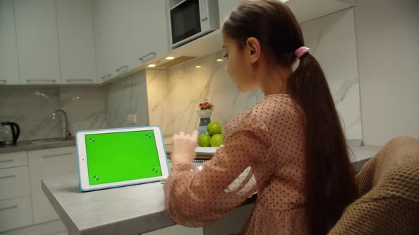 Rear View of School Girl Doing Homework Online Using Tablet Indoors alt