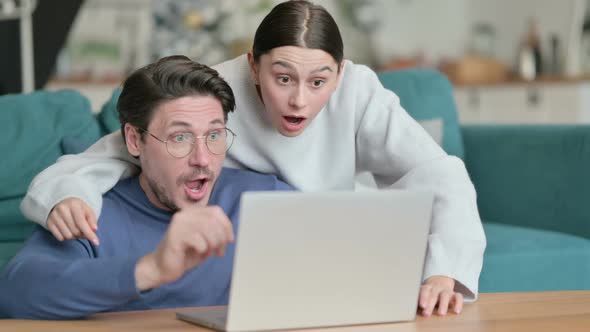 Hispanic Couple Celebrating Success While Using Laptop Together