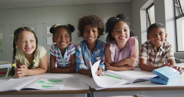 Video of happy diverse pupils learning together in classroom