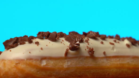 Sweet Eclair with Chocolate Sprinkles Rotating on a Wooden Table on a Blue Background