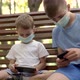 Boys in Medical Masks Play with Smartphones in the Park - VideoHive Item for Sale