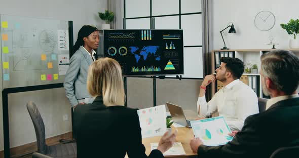 Woman Explaining Report on Digital Screen for Attantive Motivated Mixed Race Colleagues