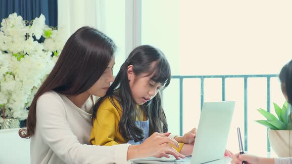 Asian single mother teaching homework to her little sibling daughter child