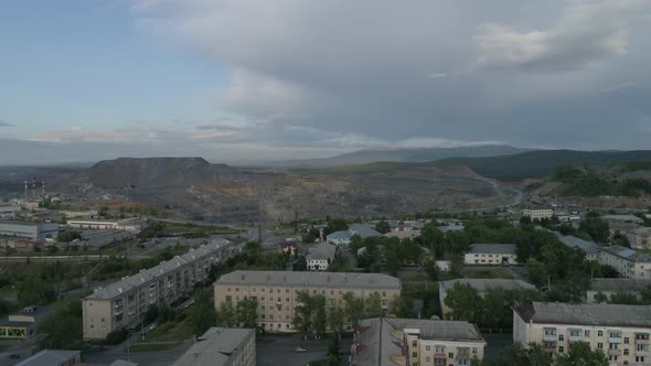 Aerial view of city with low buildings. The camera goes up and overlooks huge quarry 15