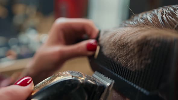 Barbershop: woman hairdresser cuts man's hair with a razor