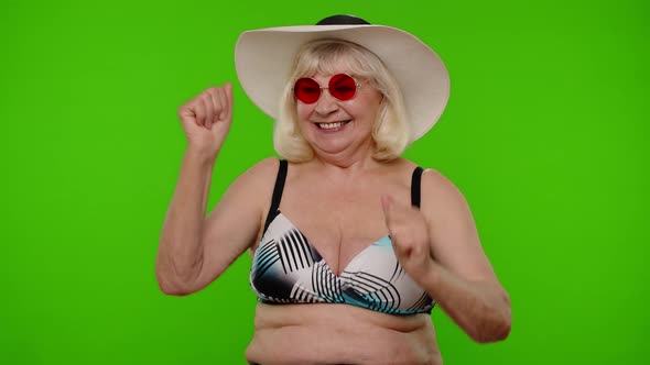 Mature Old Woman Traveler in Red Sunglasses and Hat Dancing Celebrating Smiling on Chroma Key