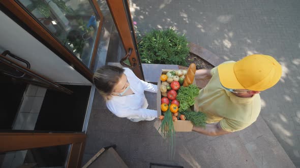 Food delivery. Social distance. Shop online. Courier with a box of vegetables.