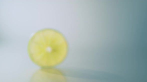 Lime slice spinning on wet surface. 4K 30fps. Slow Motion.