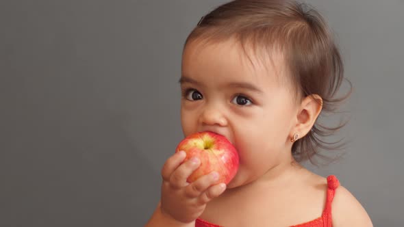 Girl Child in a Red T-shirt Eating a Red Apple