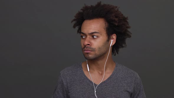 African American Young Man Listening to the Music with Headphones Then Taking It Off and Smiling