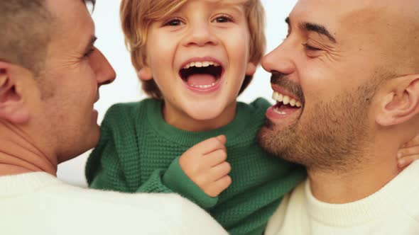 Gay Male Couple Having Tender Moment with Boy Outdoor  LGBT Family Love Concept