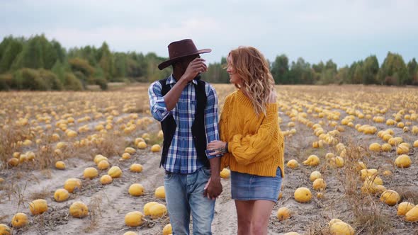 Couple Walking on Pumpkin Field Holding Hands