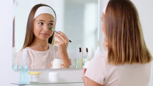 Teenage Girl Applying Mask to Face at Bathroom