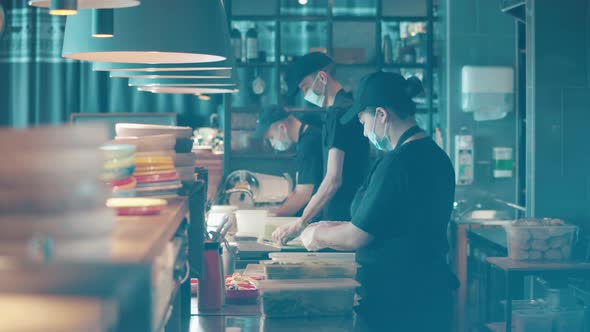 Restaurant Personnel in Face Masks are Cooking in the Open Kitchen