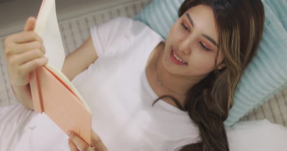 Young Beautiful Asian Girl Reading A Book On The Floor.