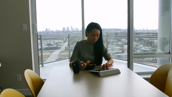 Woman using digital tablet while having breakfast