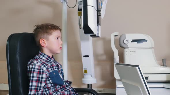 Ophthalmologist Treatment - a Little Boy Checking Eyes with Big Device By the Table