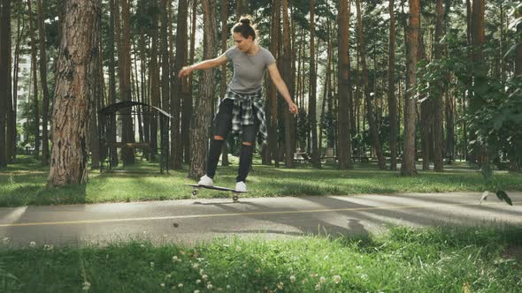 Girl falls off a skateboard. Young female learning to skating on skateboard outdoors. 