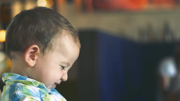 Mother Gives Baby Food From a Baby Spoon in a Restaurant, a Child Eats Willingly. .