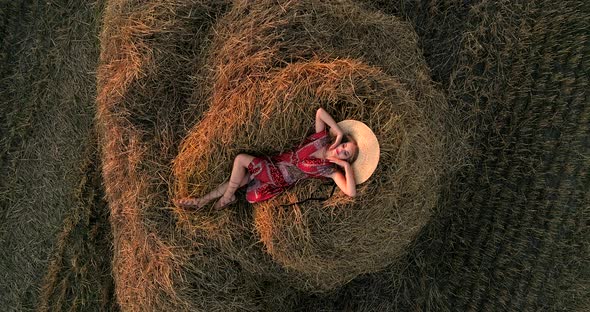 Girl Lying On A Pile Of Hay In A Field At Sunset